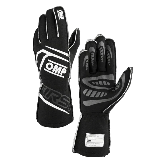 A pair of black OMP 'FIRST' Circuit Racing Gloves with visible brand logo and silicone palm for grip.
